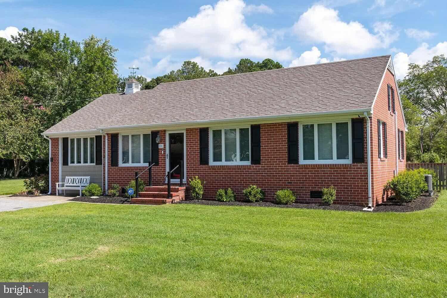 Brick ranch home with its original concrete driveway and small entry steps before the porch addition